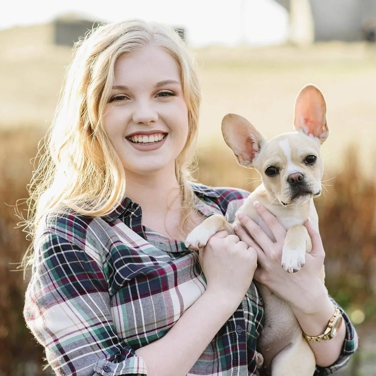 Woman smiling while holding a small Royal Frenchel puppy.