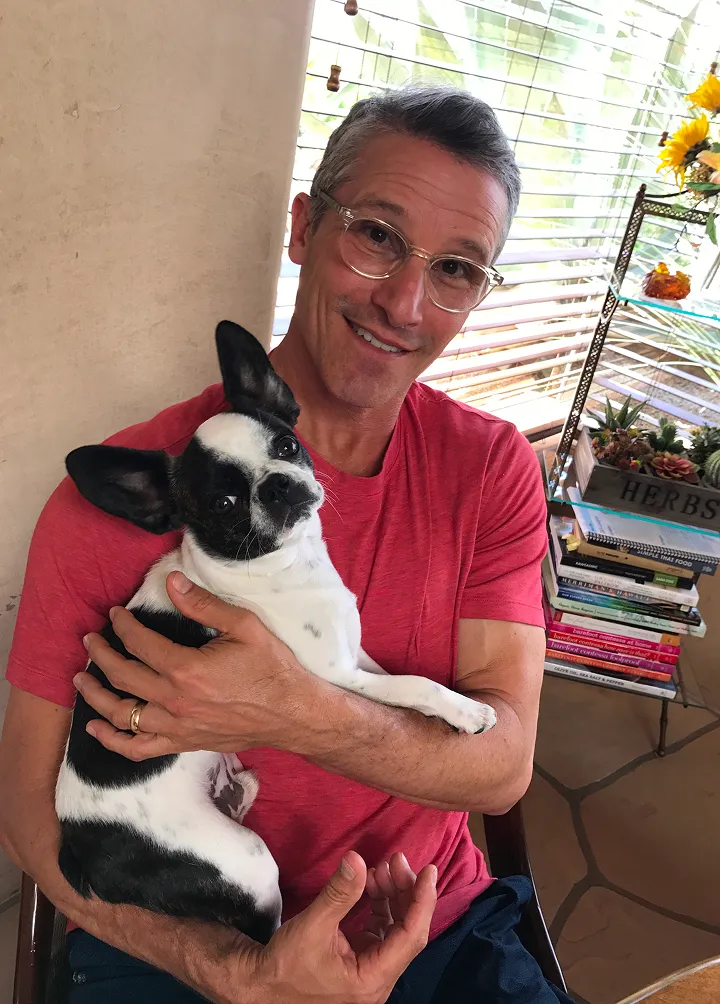 Micro Mini Royal Frenchel being held by a smiling owner in an apartment.