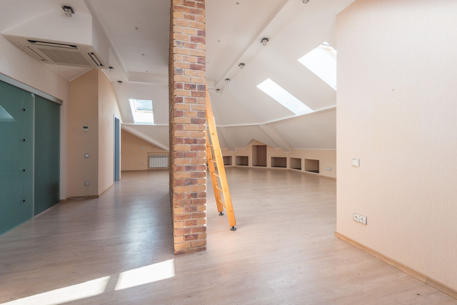 Combles aménagés, poutre apparente et cloison en briques sous des fenêtres de toit — pose de Velux à Pacé par Avenir Eco Couverture