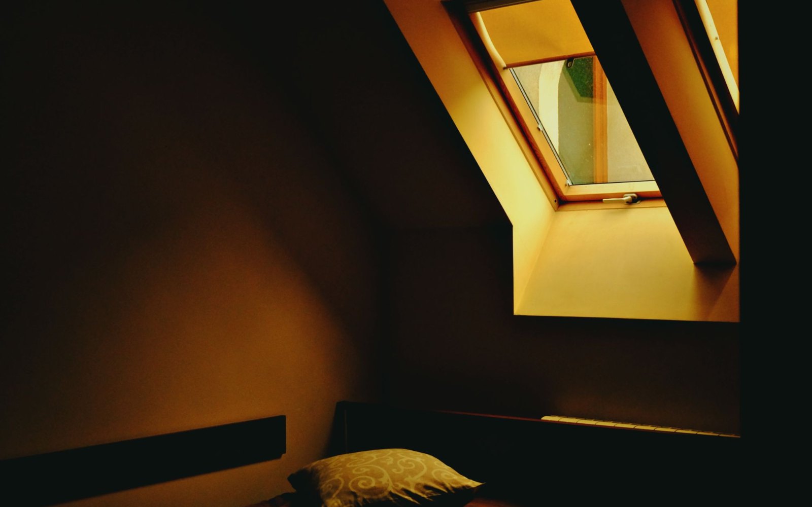 Chambre sous les combles plongée dans le noir, fenêtre de toit occultée — volets roulants VELUX posés à Rennes par Avenir Eco Couverture