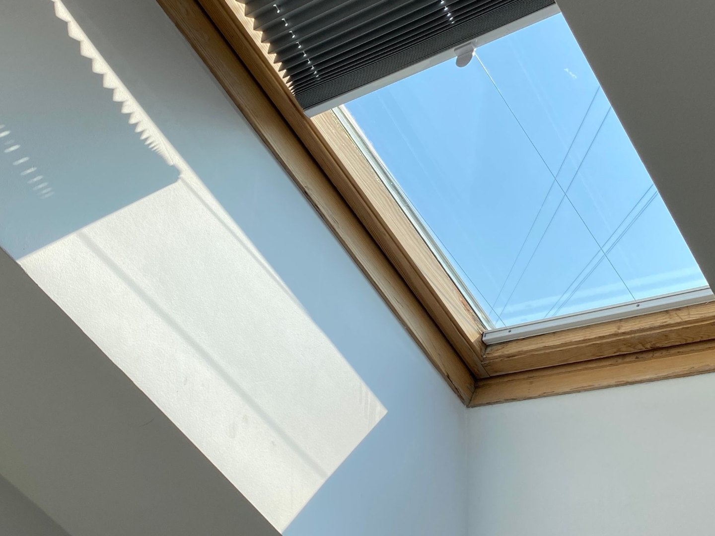Fenêtre de toit équipée d’un store intérieur filtrant la lumière dans une pièce claire