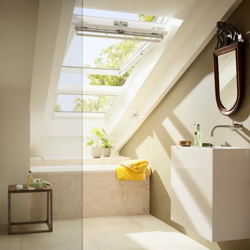 Salle de bains sous rampant éclairée par une fenêtre de toit au-dessus de la baignoire