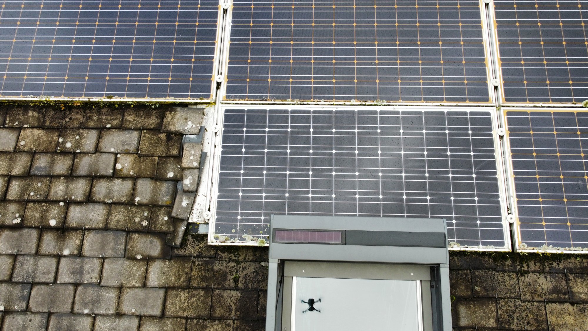 Avant : vue aérienne de la toiture fibre-ciment moussue et des anciens panneaux solaires — La Mézière