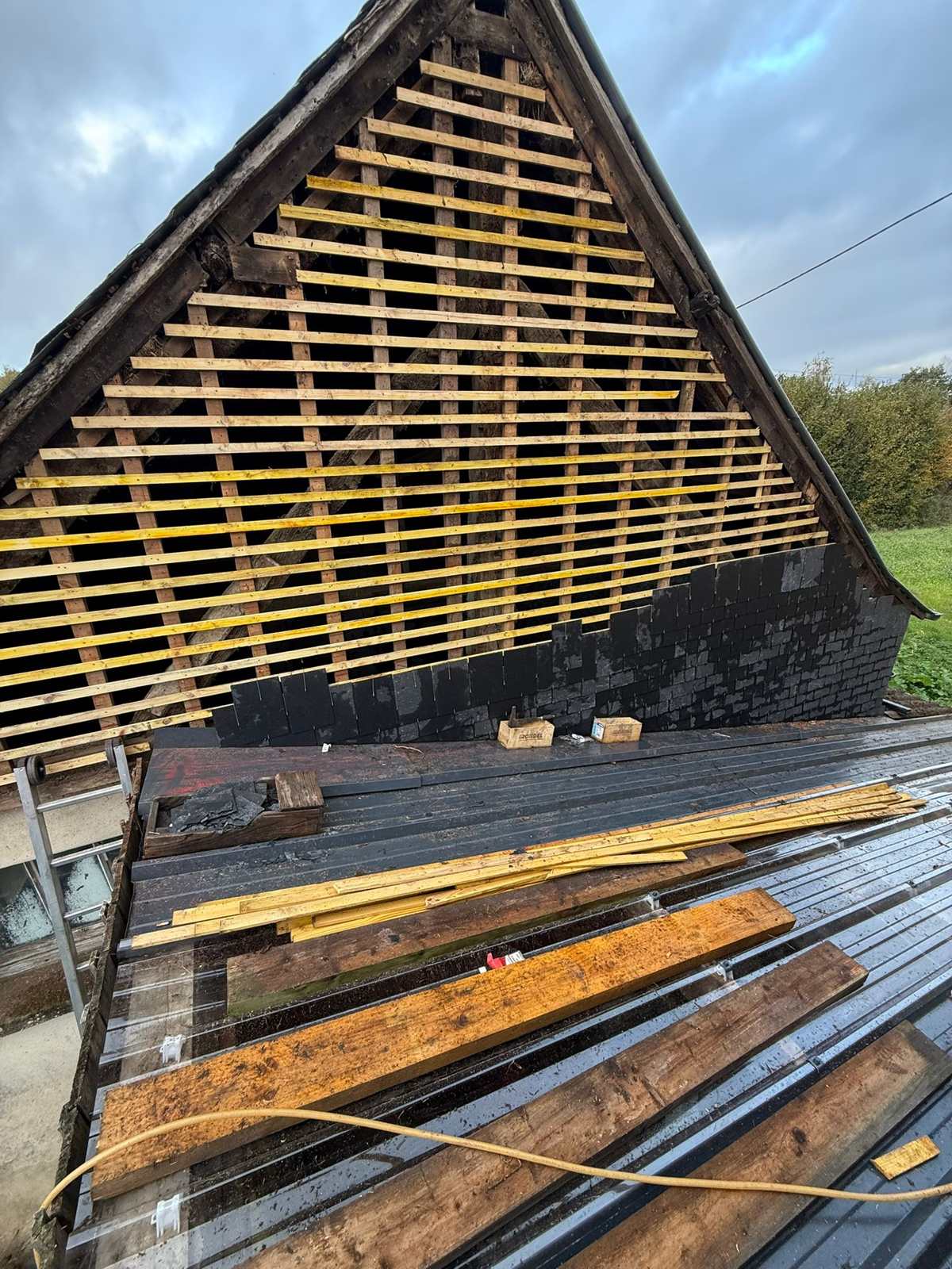 Premiers rangs d'ardoise naturelle posés sur le liteaunage du pignon à Pacé