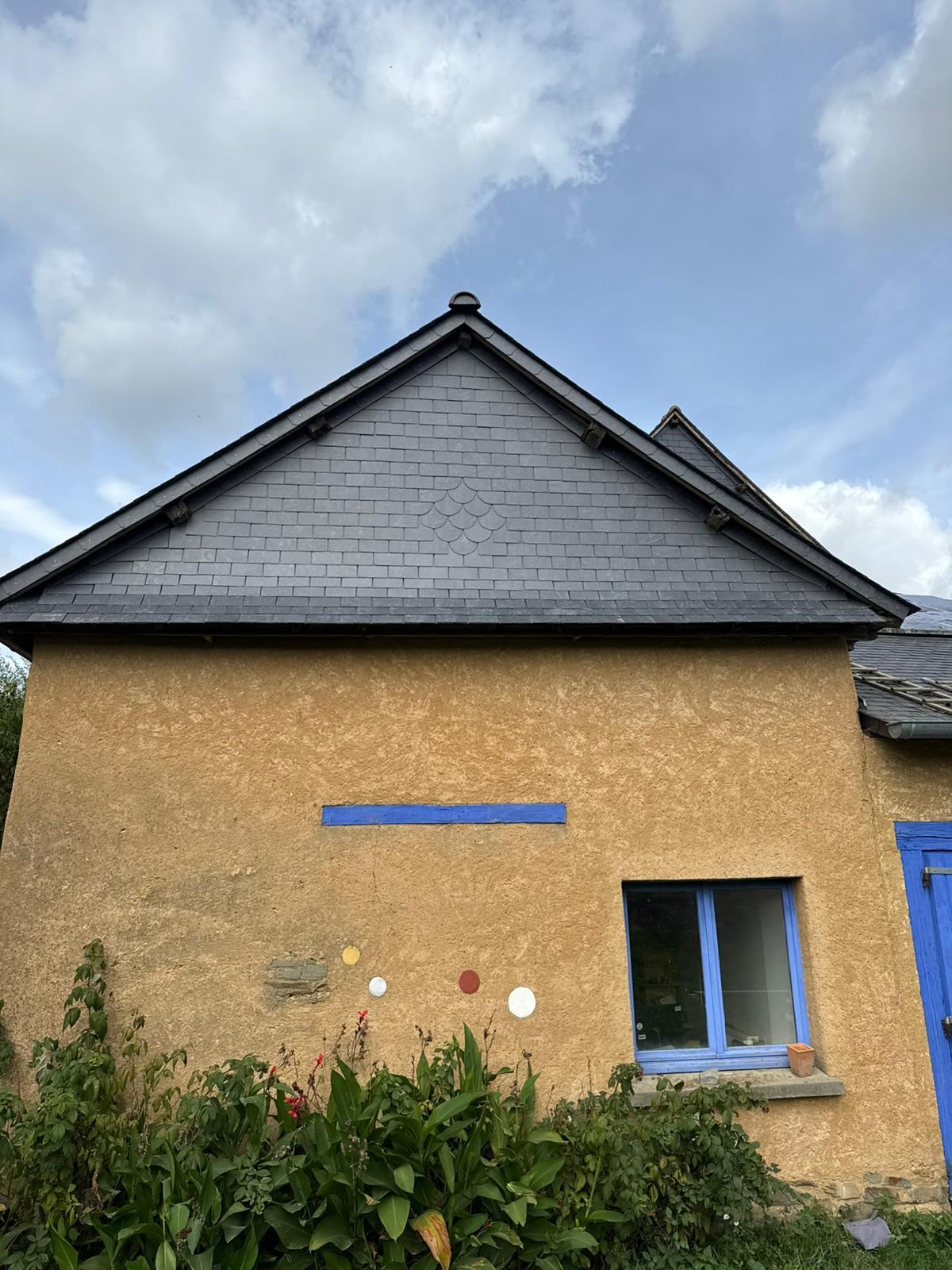 Pignon terminé en ardoise naturelle avec son motif décoratif, façade en terre et menuiseries bleues à Pacé