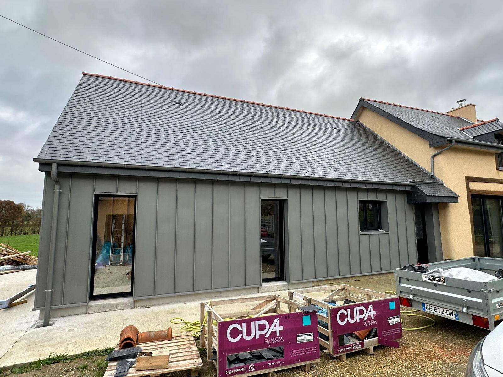 Façade en zinc quartz et toiture en ardoise naturelle, palettes d'ardoise au pied du chantier à La Mézière