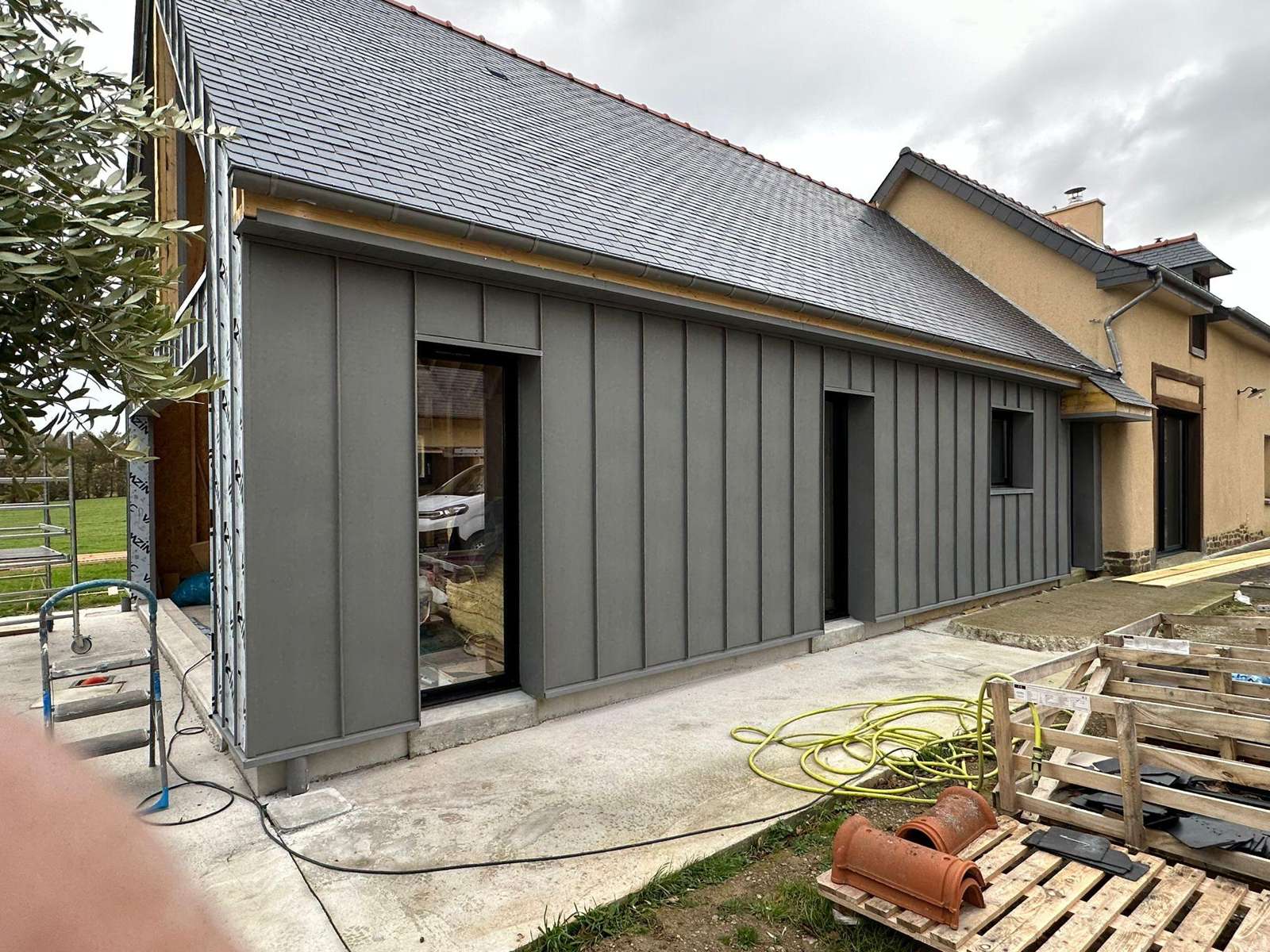 Façade côté cour en zinc quartz sous la toiture en ardoise, raccordée à la maison existante à La Mézière