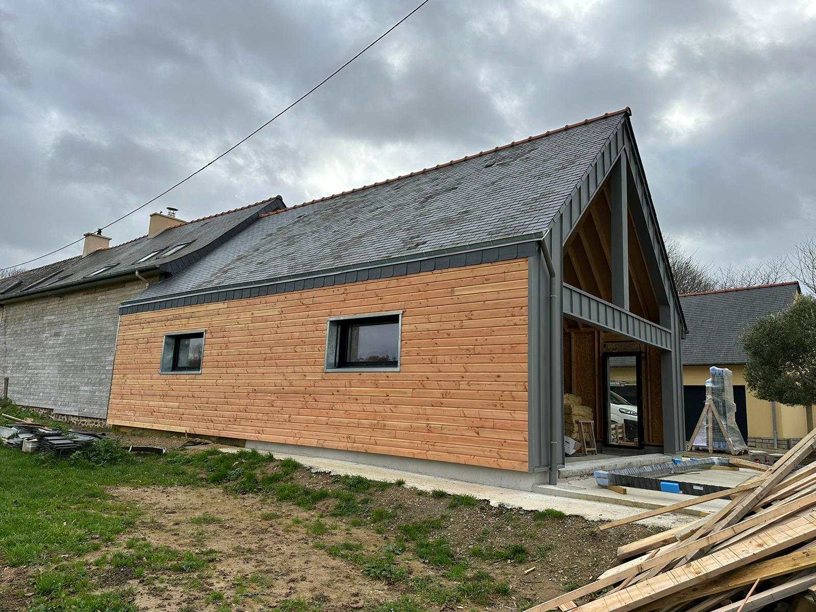 Façade côté jardin en bardage bois sous la toiture en ardoise, pignon habillé de zinc quartz à La Mézière