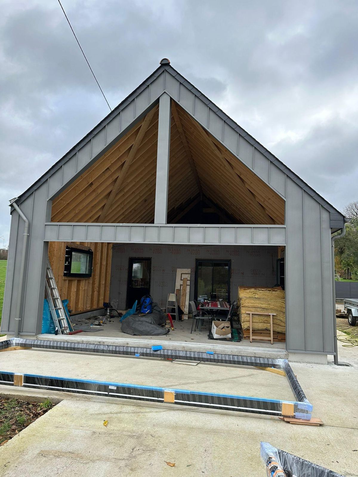 Vue d'angle du pignon en zinc quartz et de la façade côté cour en cours de chantier à La Mézière