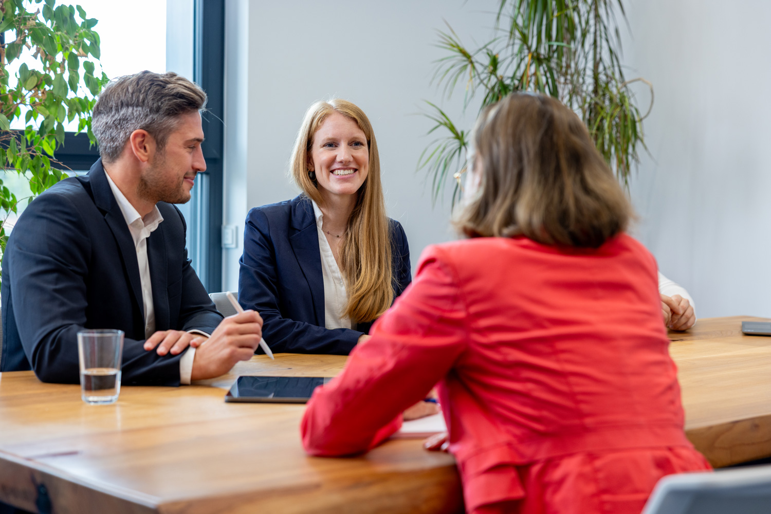 Drei Personen in Besprechungssituation an einem Konferenztisch.