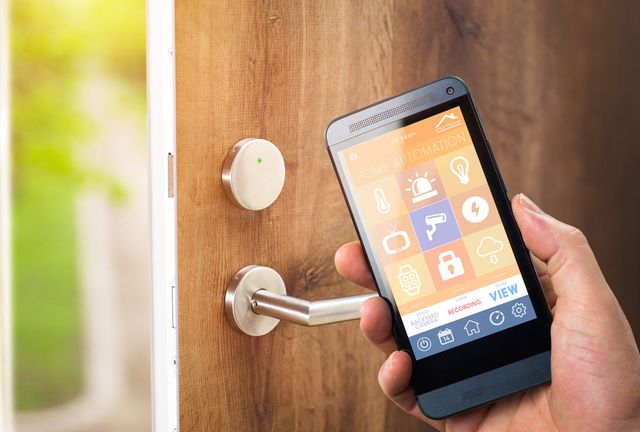 person holding phone with home alarm system on the screen