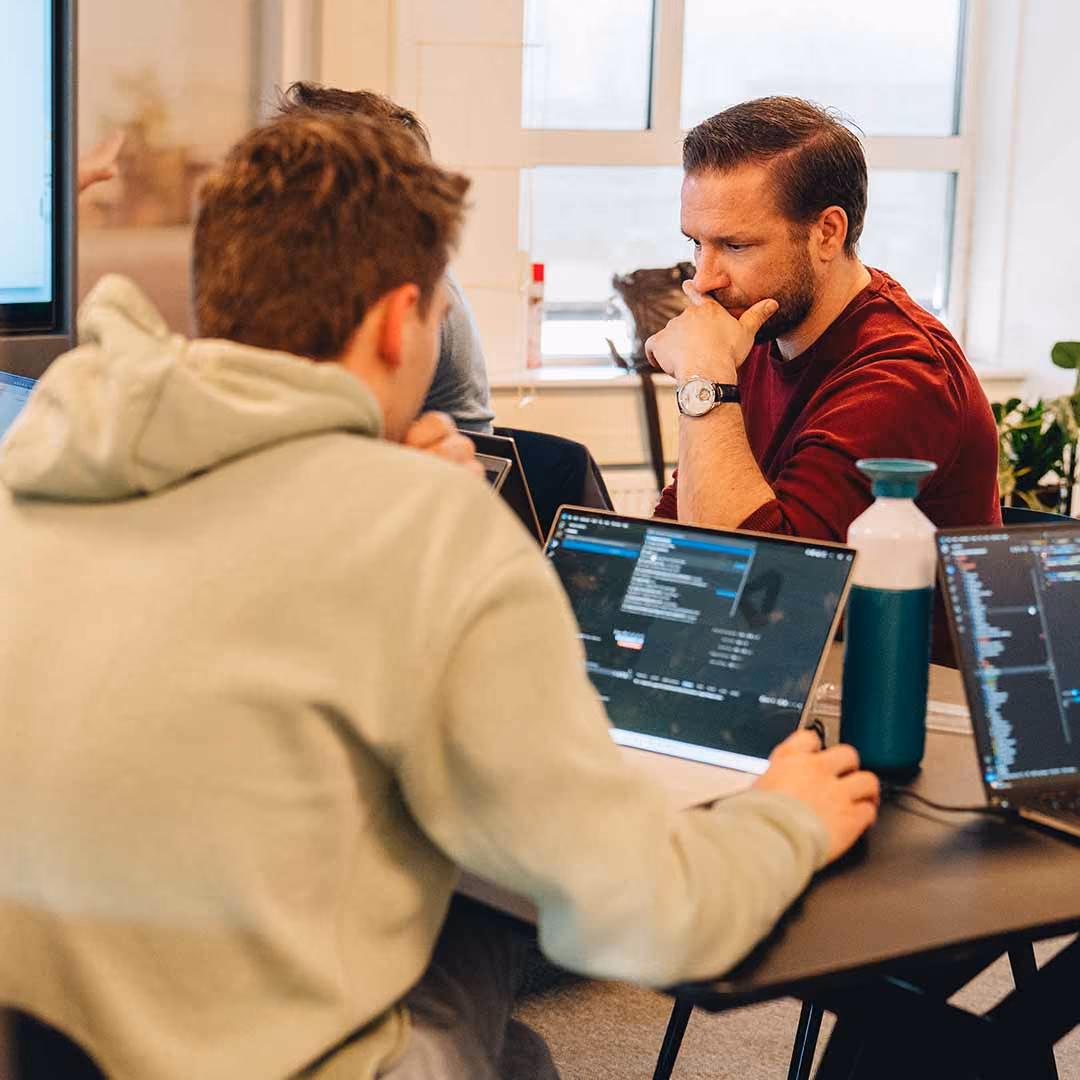 Twee mannen werken geconcentreerd op laptops in een lichte kantooromgeving.