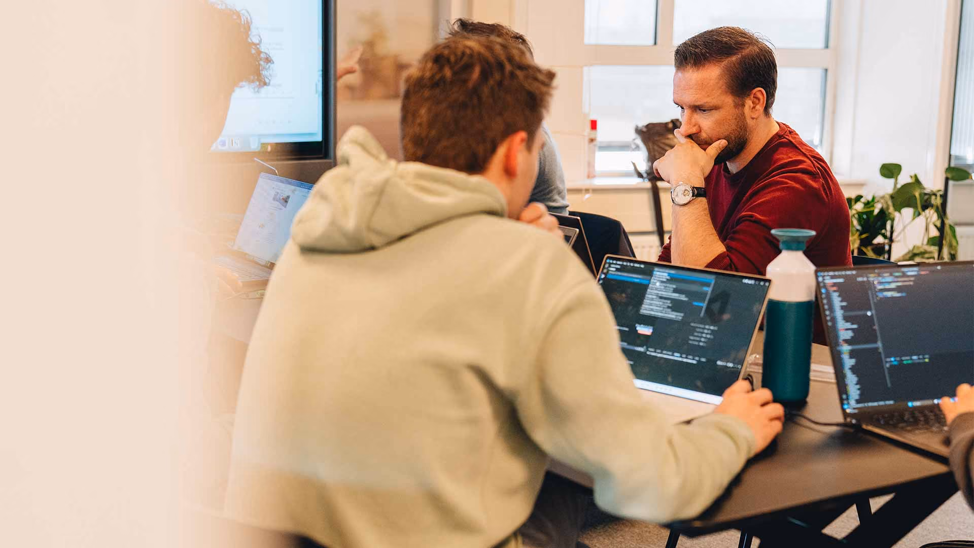Mensen werken geconcentreerd aan laptops in een kantoorruimte met natuurlijk licht.