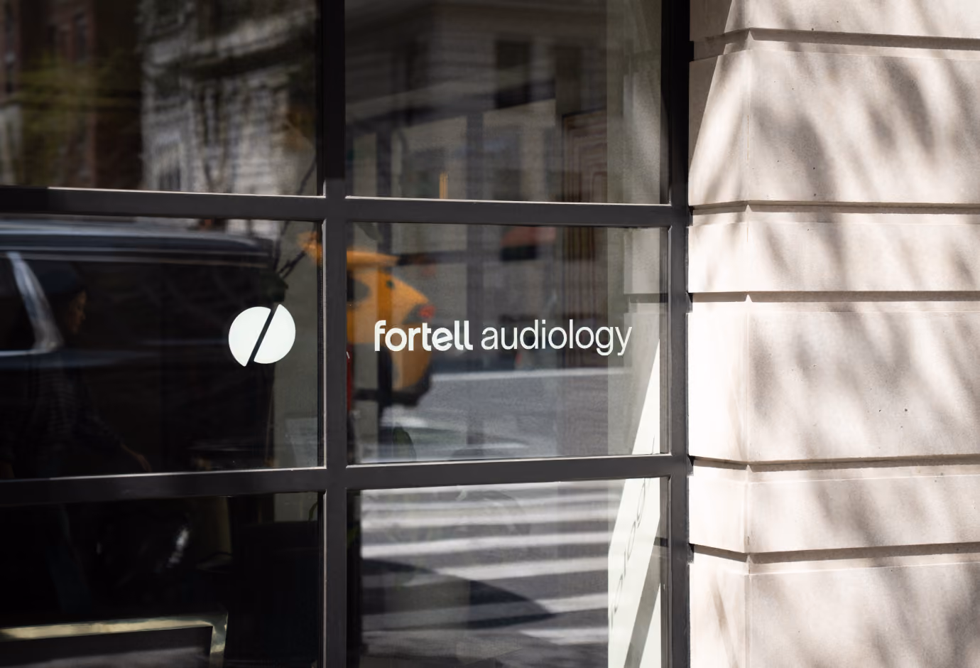 Fortell Audiology logo on a clinic window facing a city street.