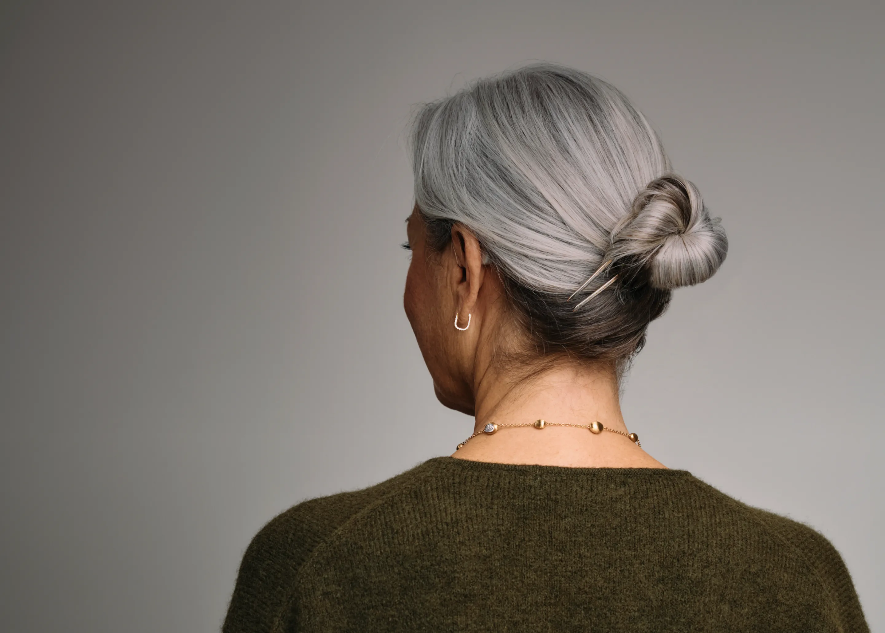 Woman wearing Fortell hearing aids, seen from behind
