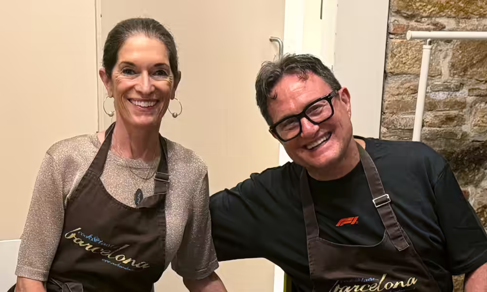 Smiling couple in matching Barcelona cooking-class aprons.