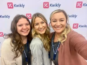 Three members of the Kwikly team pose in front of a back drop at the Western Regional Dental Experience convention in Phoenix, Arizona.