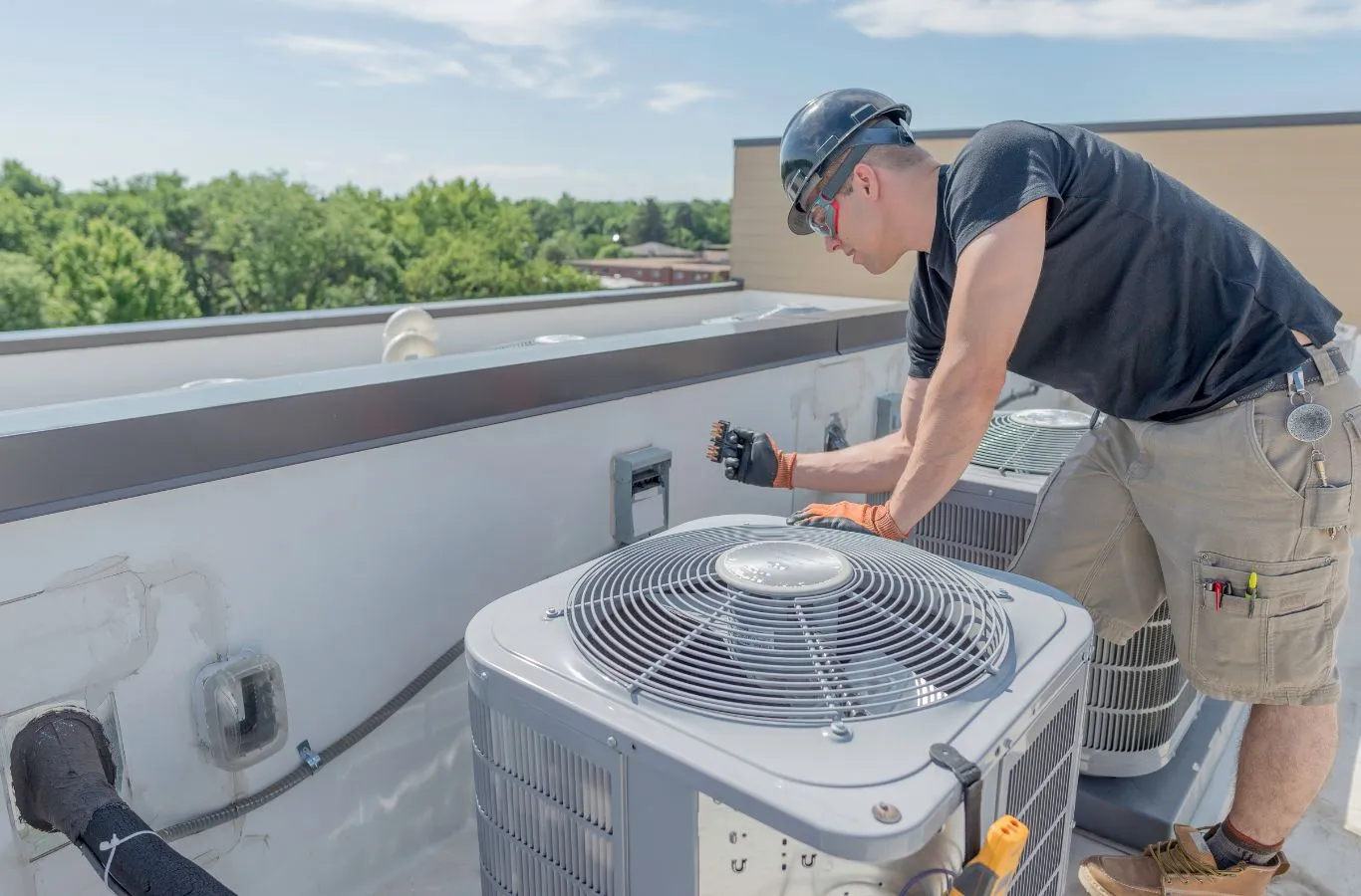 HVAC technician in a hard hat servicing a rooftop AC condenser during HVAC service in Brandon, FL.