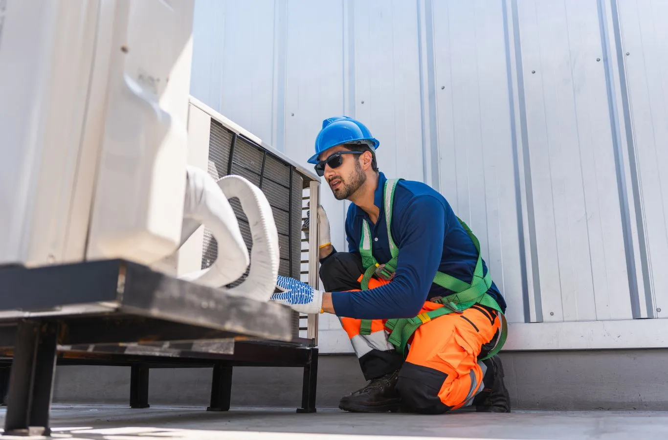 HVAC technician in a hard hat kneeling to inspect a condenser fan during HVAC service in Riverview, FL.