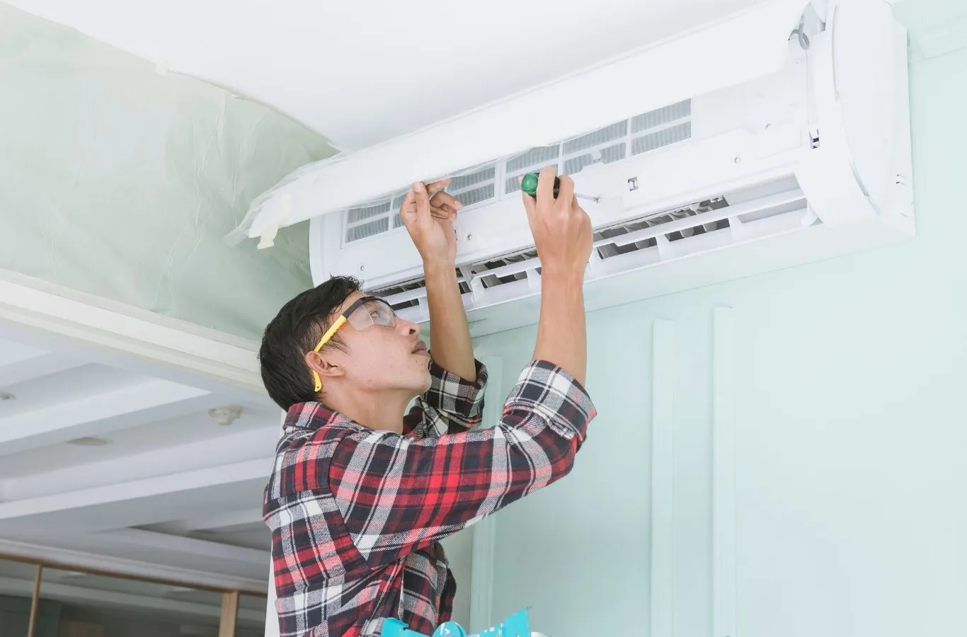 HVAC technician servicing a wall-mounted indoor AC unit. HVAC Contractor Near Me.