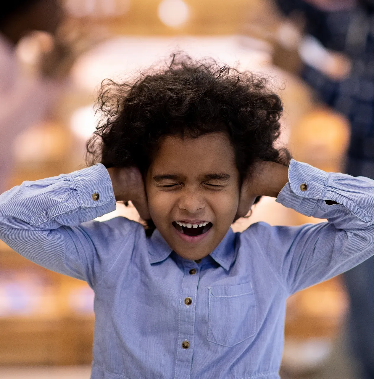 Young boy covering his ears, showing signs of overstimulation and emotional stress, illustrating challenges faced by families during educational support.
