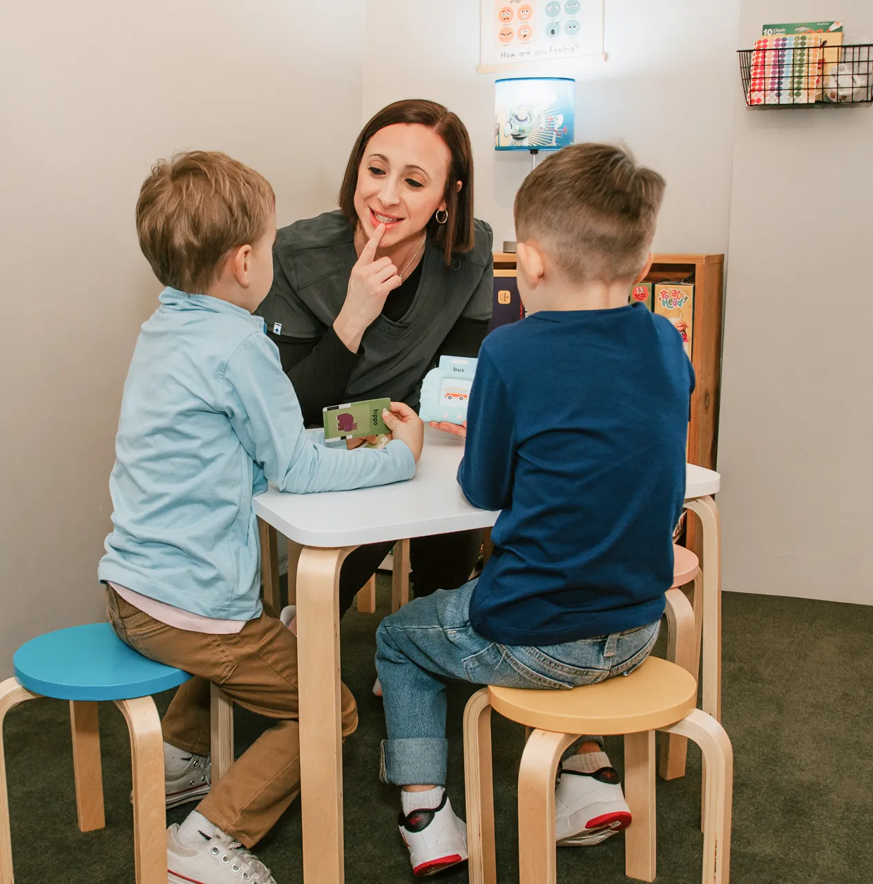 Mother supporting her young child showing signs of delayed speech and language development during a therapy session.