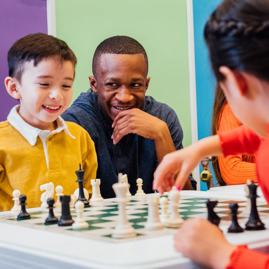 Children learning chess with a friendly coach in a colorful classroom environment