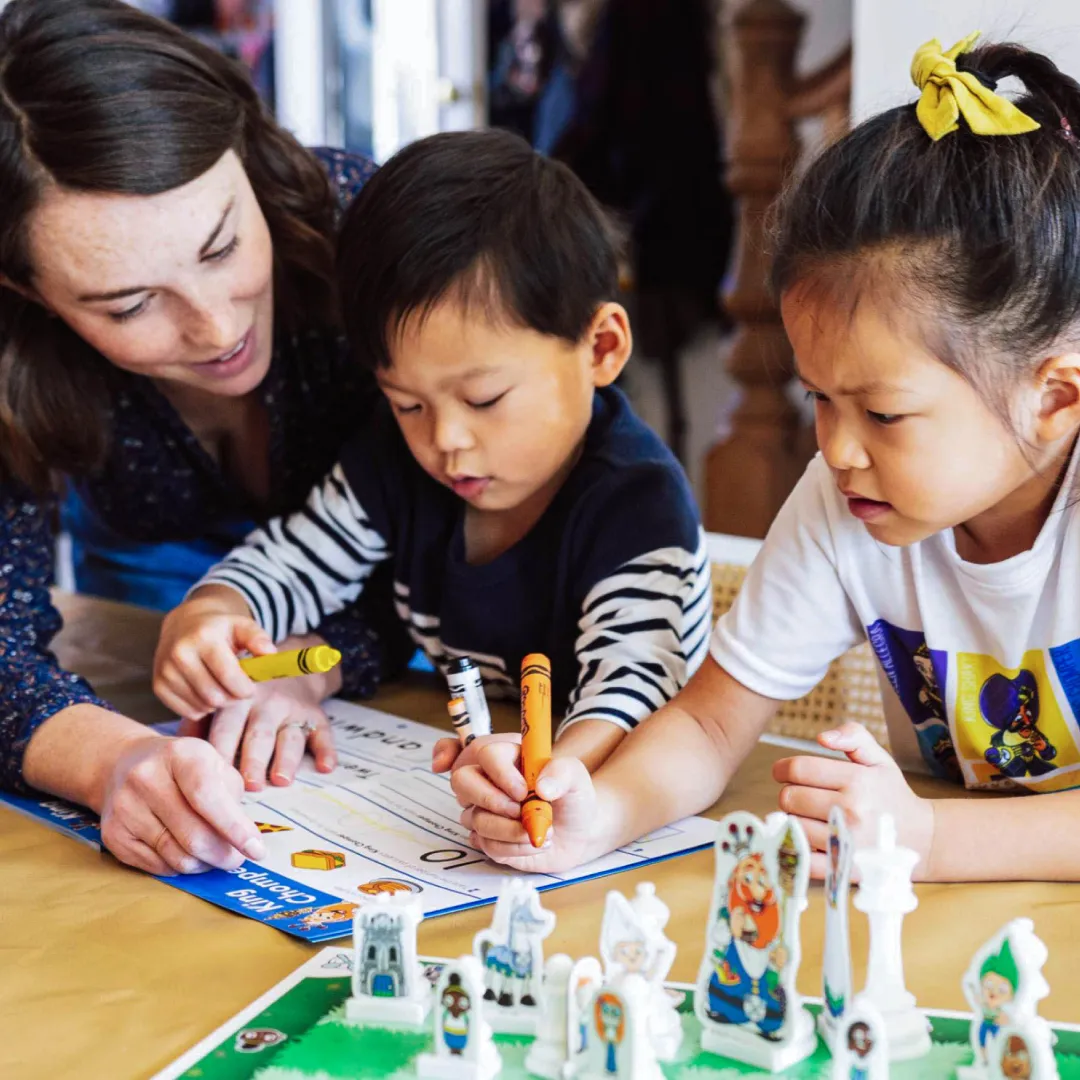 Teacher guiding two young children through a fun chess activity with Chess at Three materials