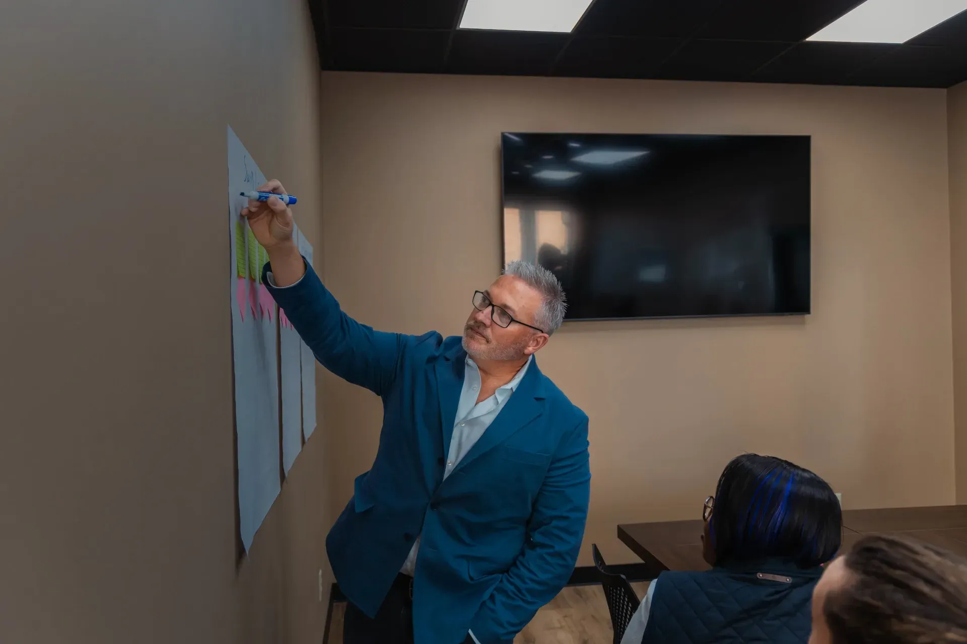 man pointing to white board with marker