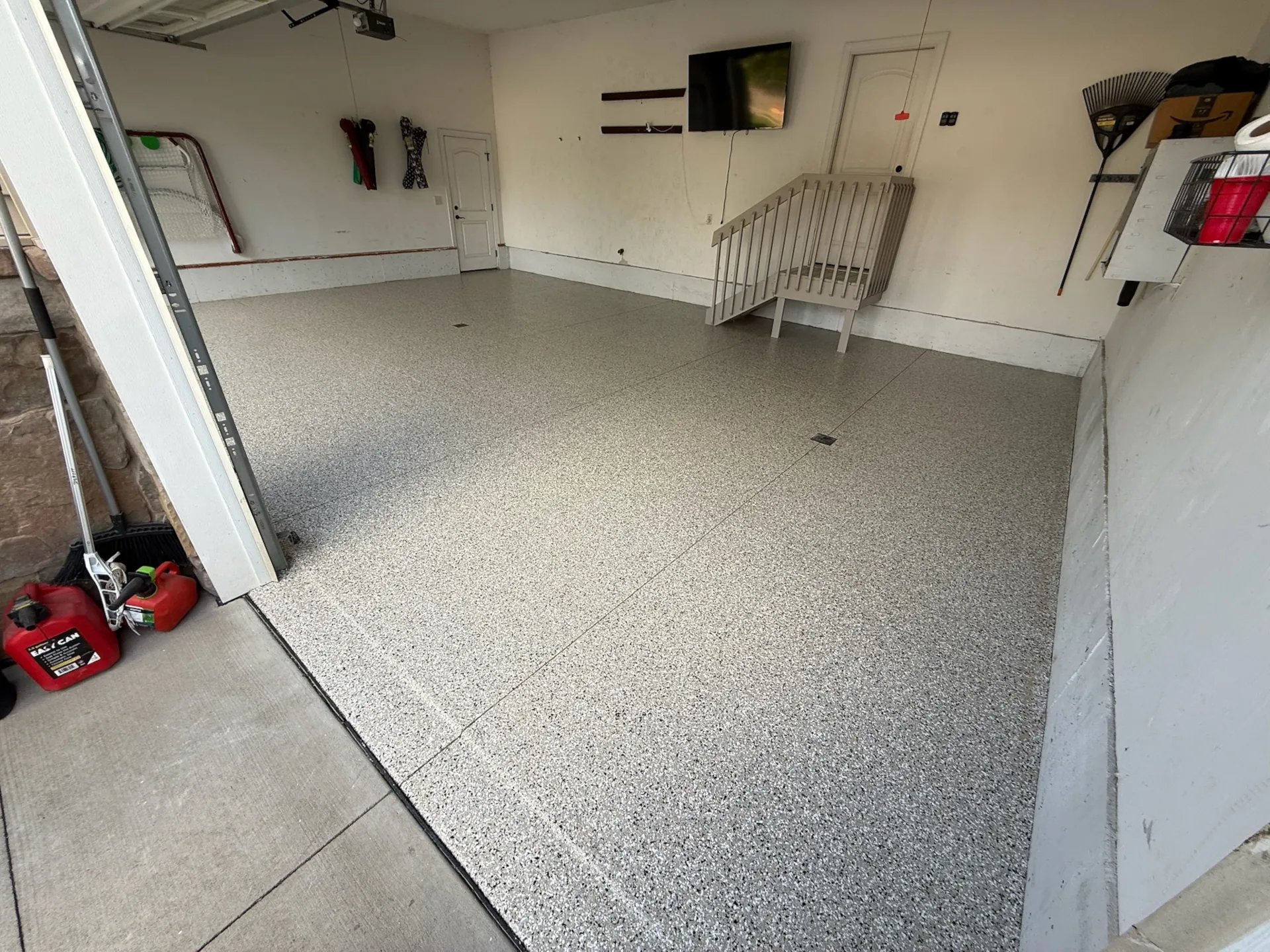 Light gray flake floor in a two-car garage, step with railing and a center floor drain in view.