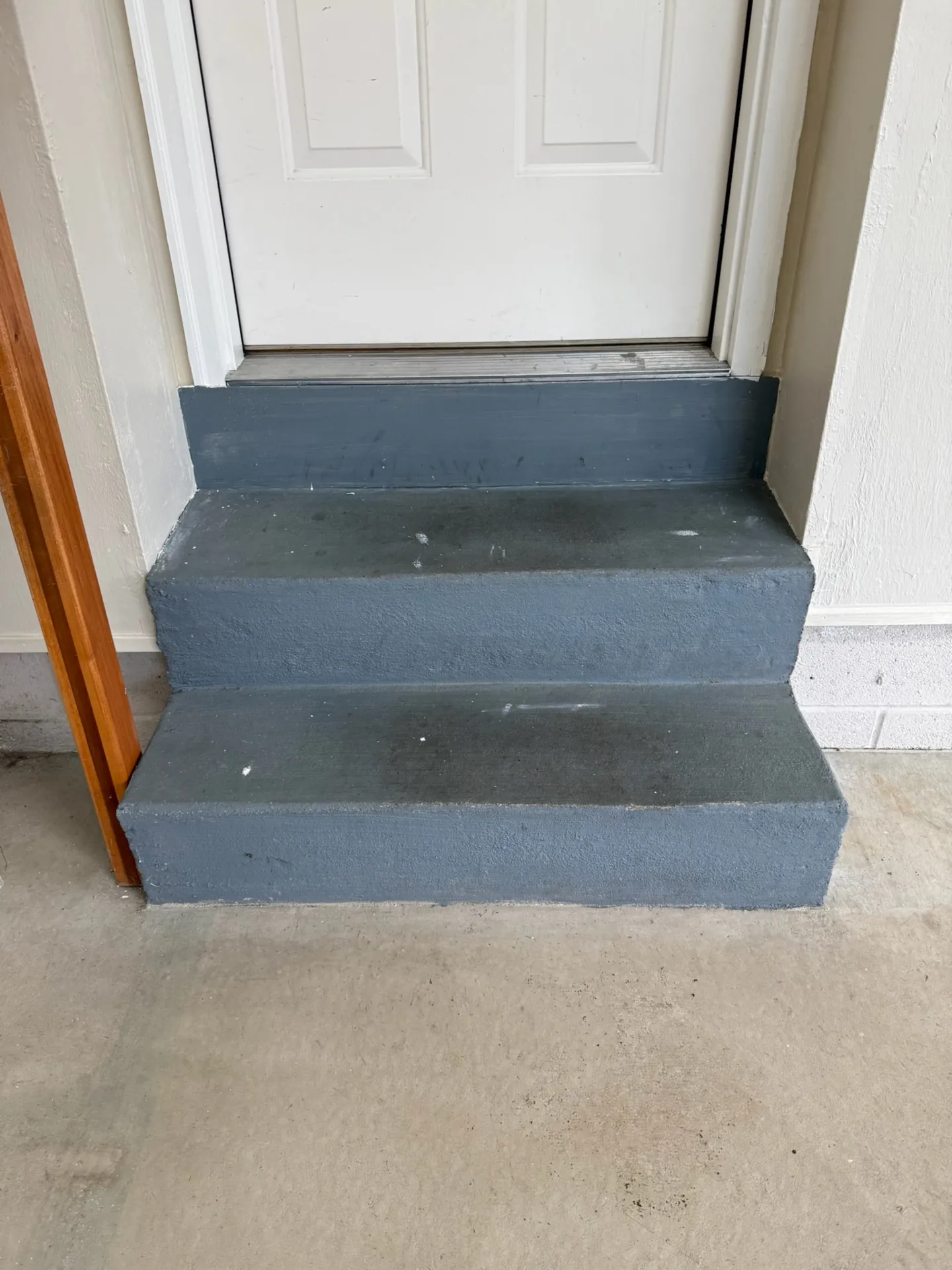 Painted concrete garage steps in dark gray with visible scuffs and paint drips on the treads and risers.