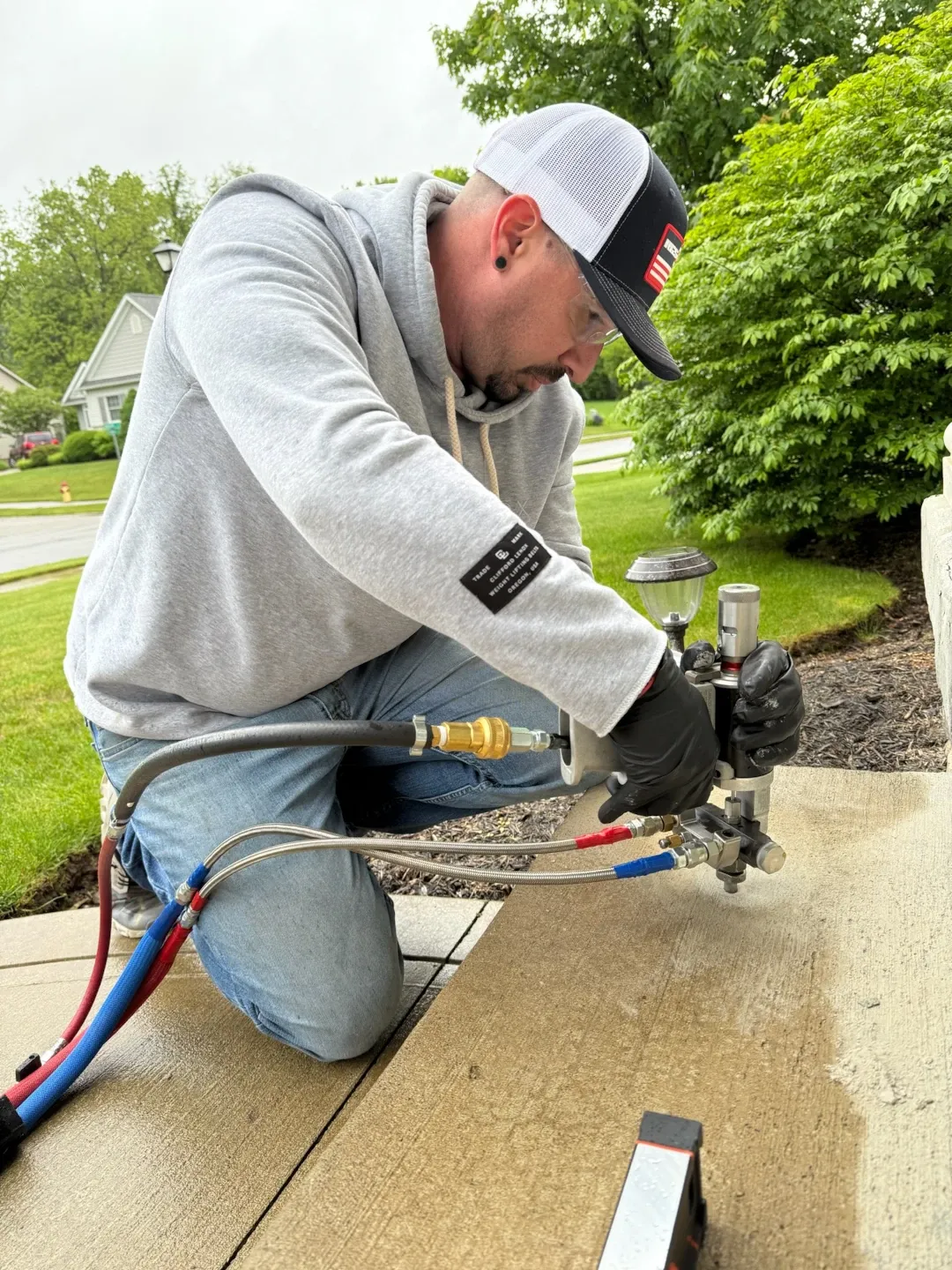 polyguys worker using a device drilled into a concrete step to lift it