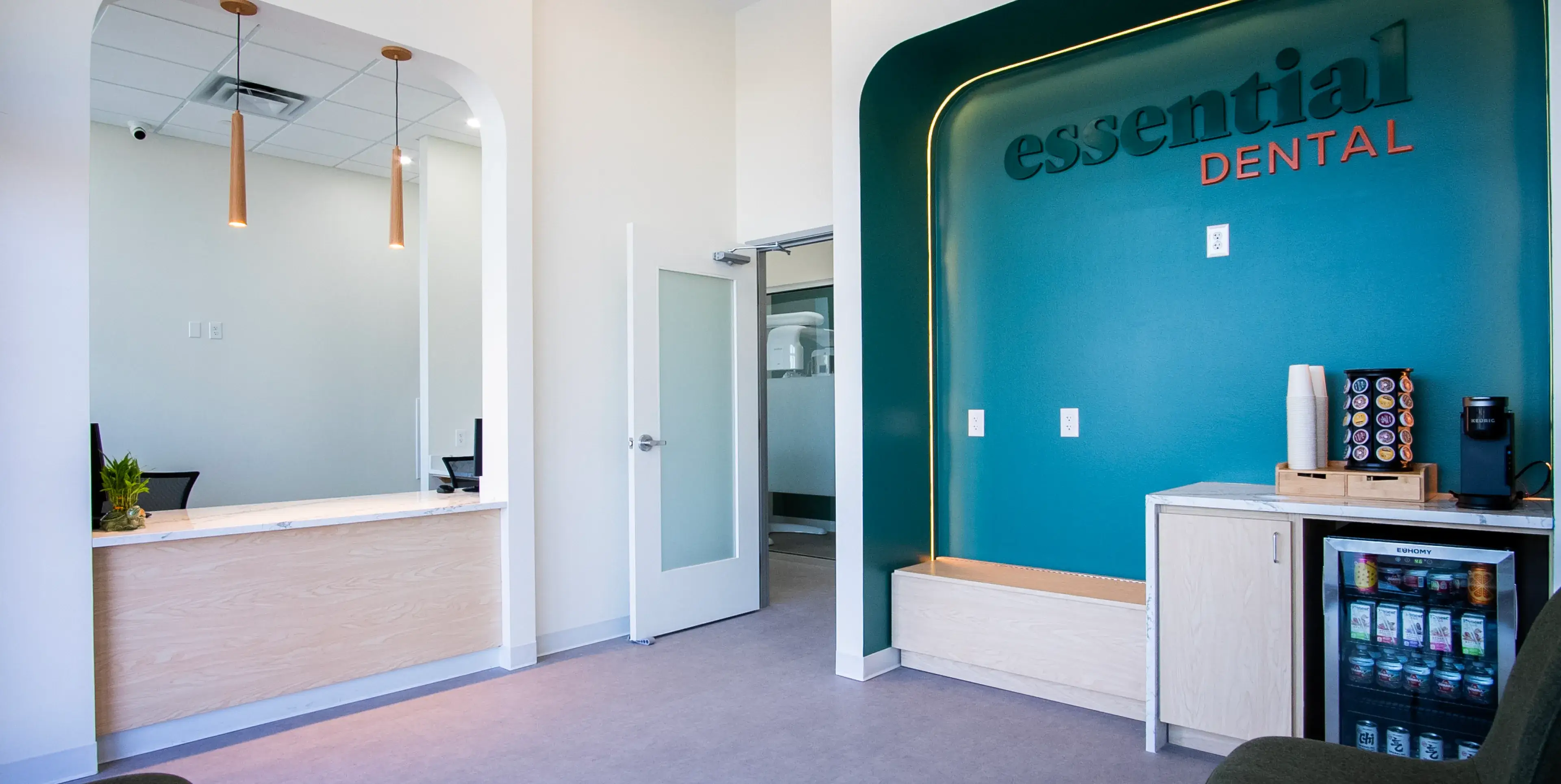 Dental office reception area with a sign reading "Essential Dental" and a coffee station on the right.