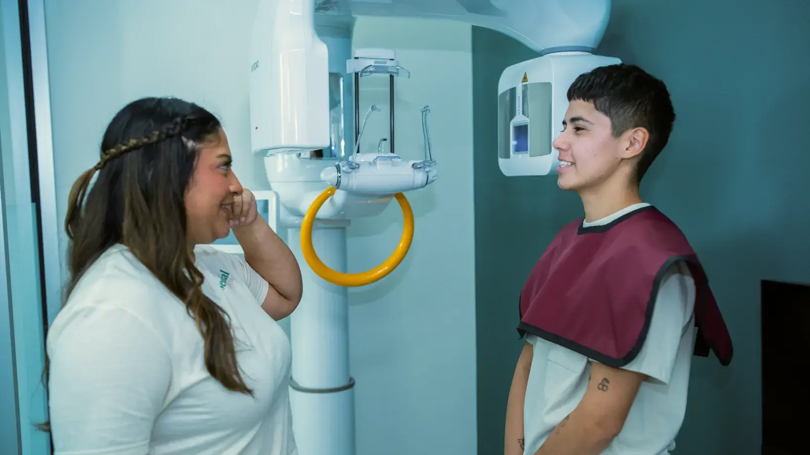 A dental technician prepares a patient for an X-ray in a dental office.