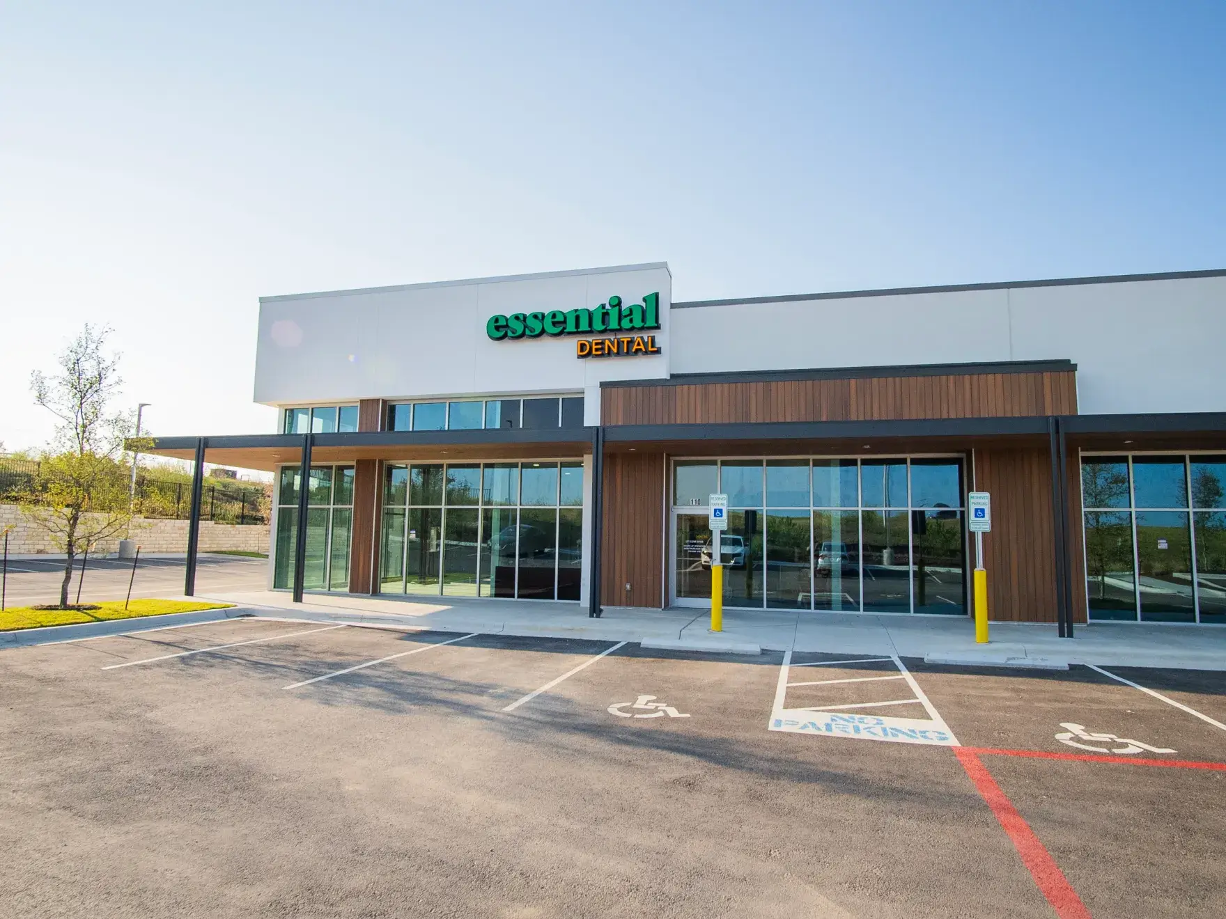 Exterior view of a modern dental office building with a sign reading "Essential Dental" above the entrance.
