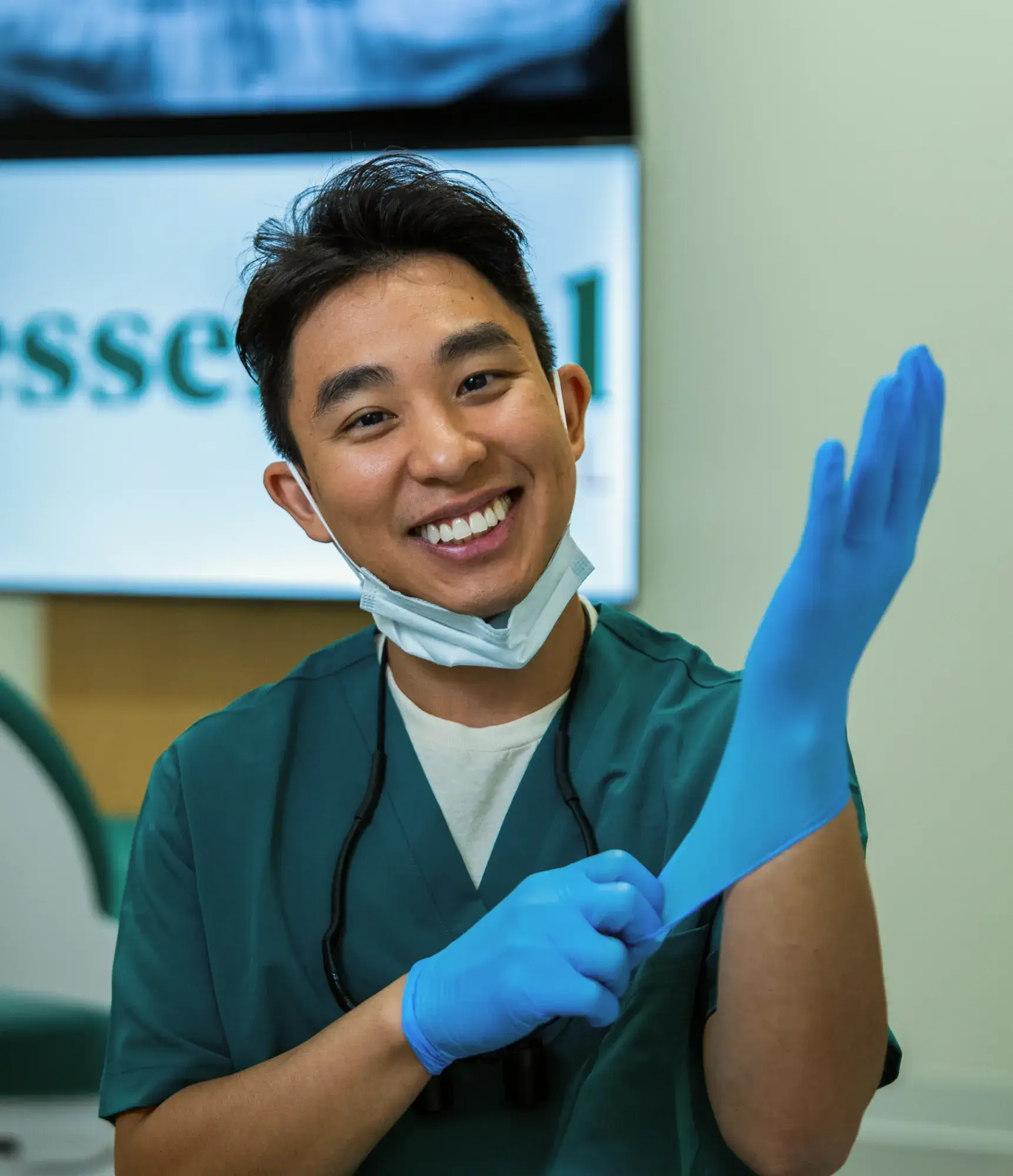A dentist smiles while putting on a blue glove, preparing for a procedure.