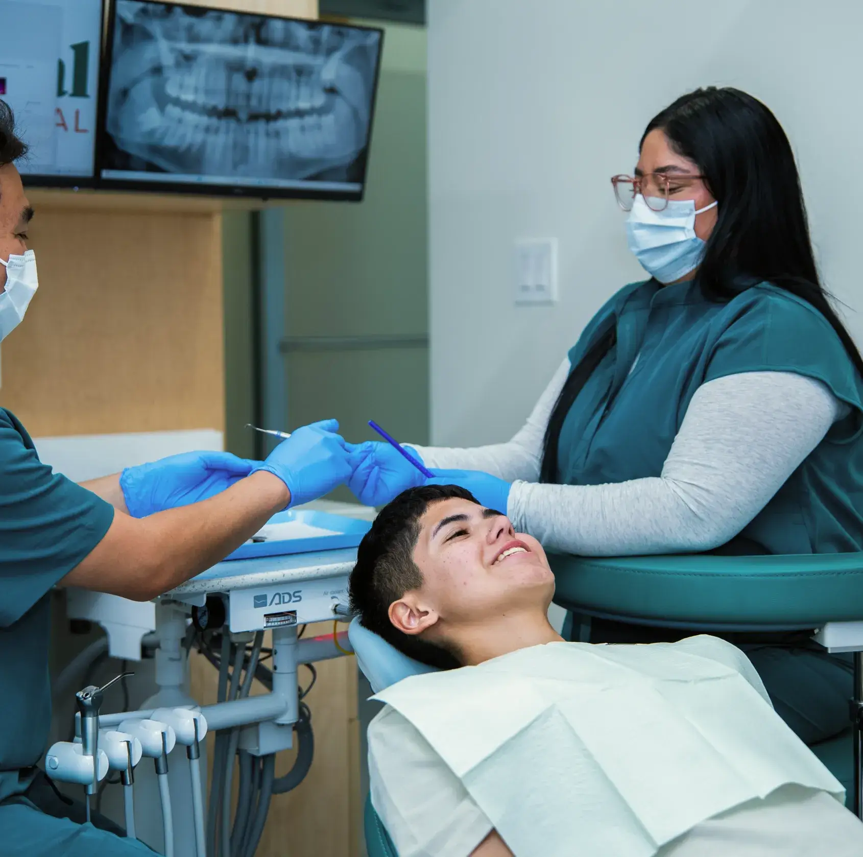 A dentist and assistant examine a patient's teeth in a dental office.