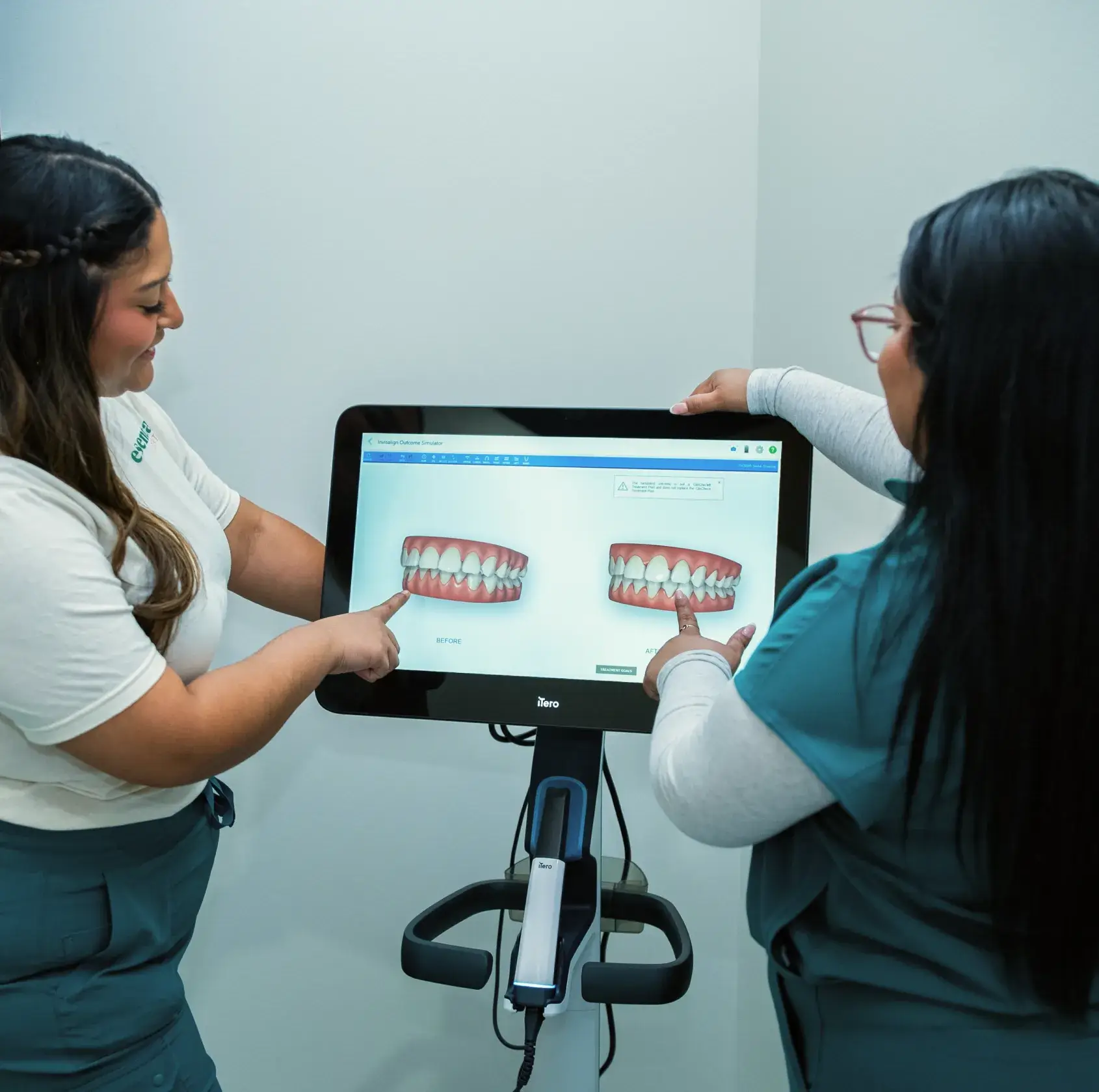 Two people discussing dental images on a screen in a medical setting.