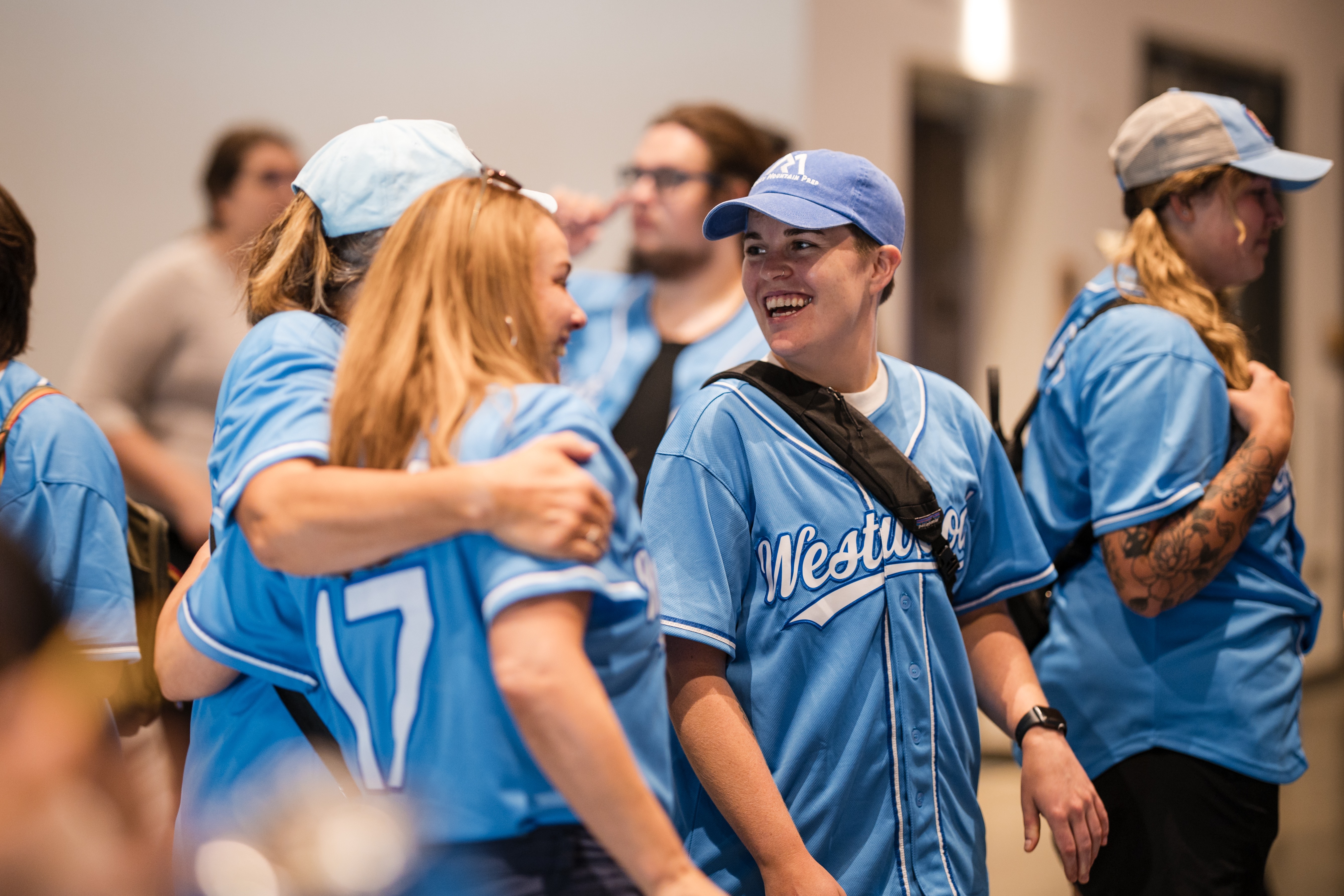 a group of people in blue baseball shirts hugging and smiling
