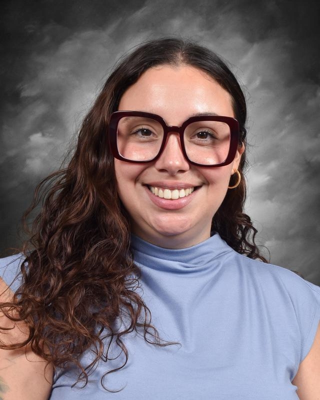 woman with ldreadlocs in a grey blazer and a black top.