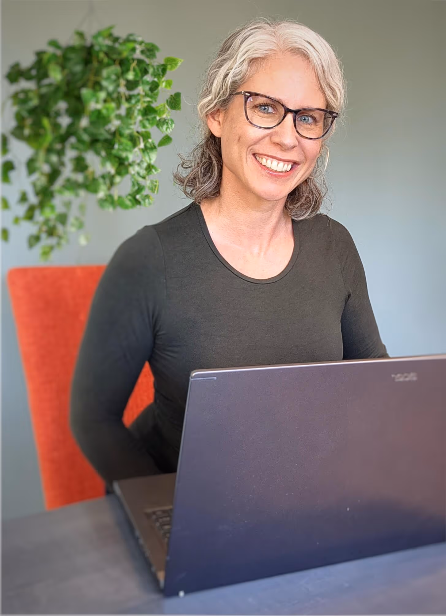 image of dr jacqueline belanger using a laptop while smiling at the camera