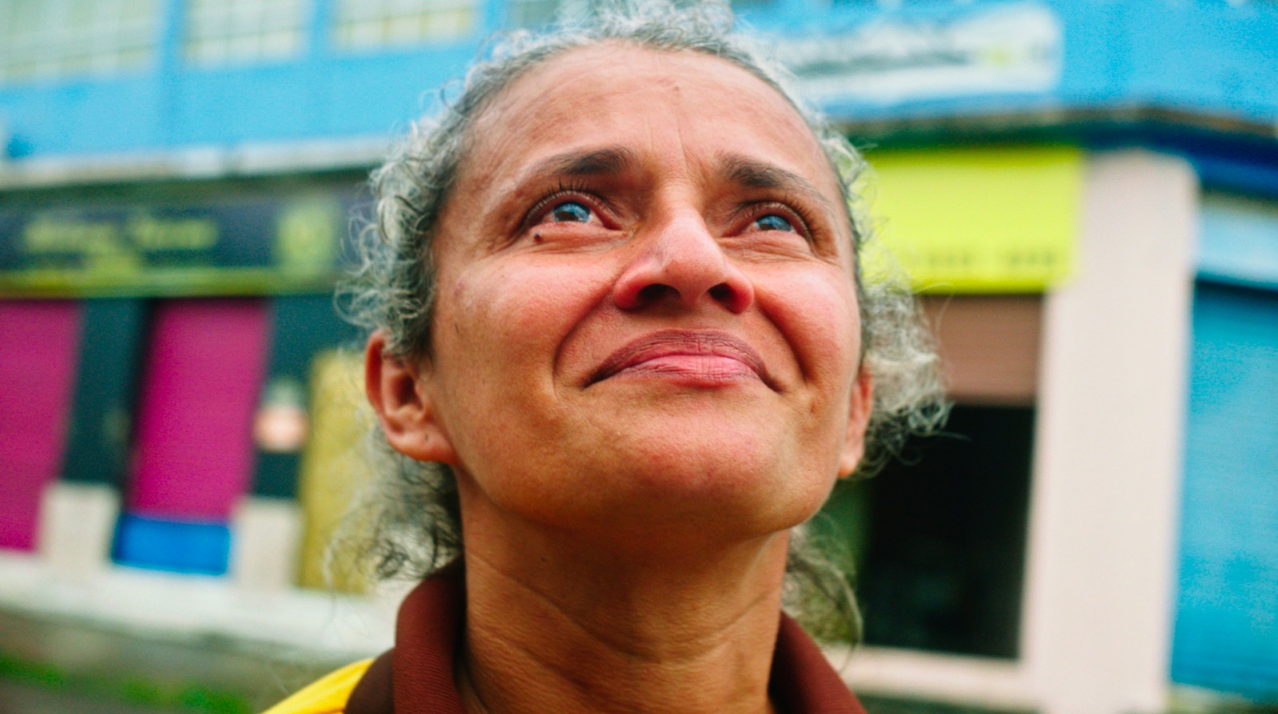 A powerful, portrait-like still of an entrepreneur from the 'Todo Dia é Dia' series, looking up with a resilient expression.