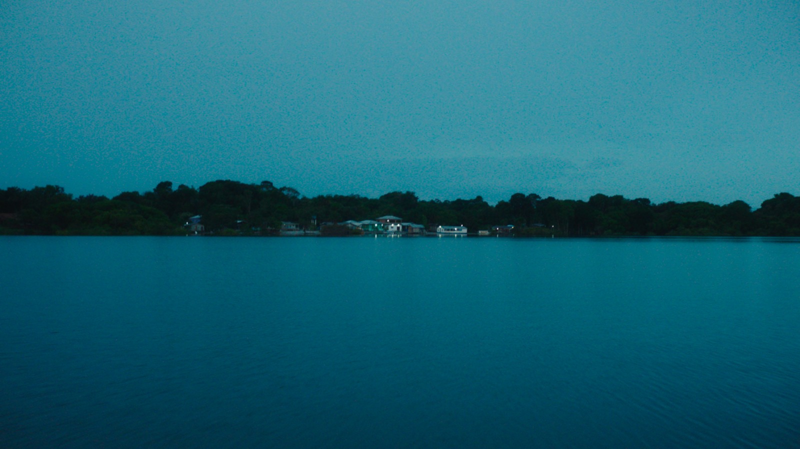 A cinematic establishing shot of a remote Amazon village at twilight, from the documentary series 'Todo Dia é Dia'.