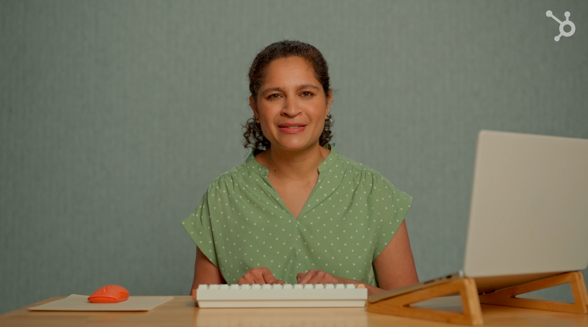A presenter smiles at the camera during a clean, direct-to-camera product demo for the HubSpot 'Spotlight' series.