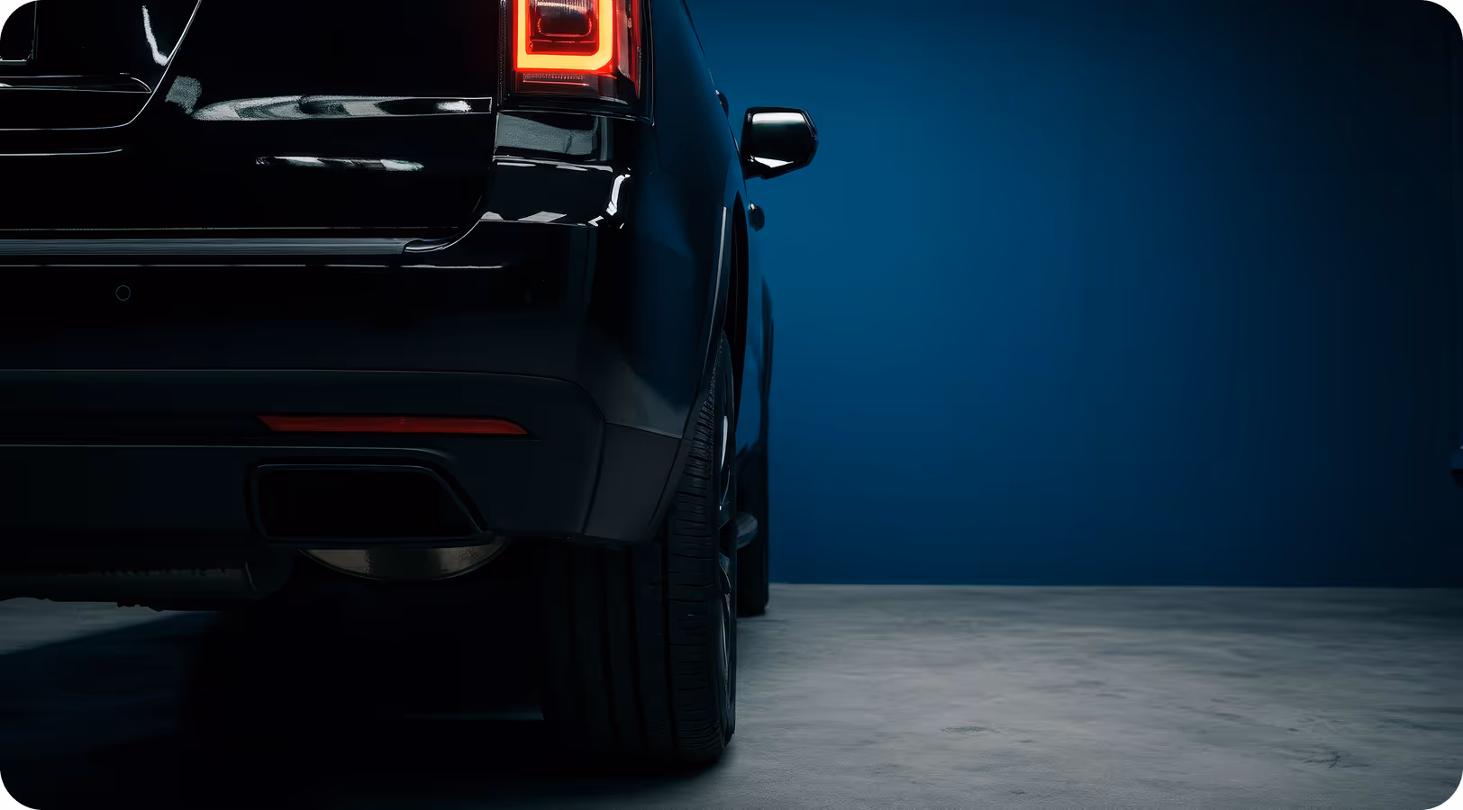 Rear view of a black car parked against a dark blue background.