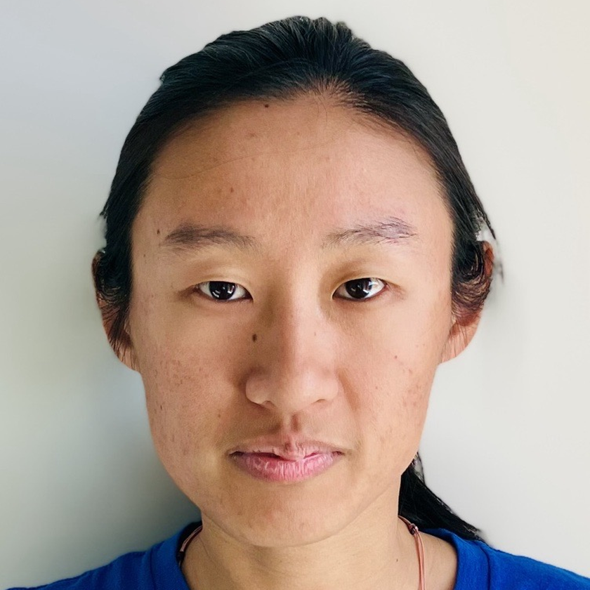 Jay Famiglietti, a man with short gray hair, a neatly trimmed beard, and glasses, smiling in a plaid blazer and collared shirt, standing outdoors with blurred architecture and greenery in the background.