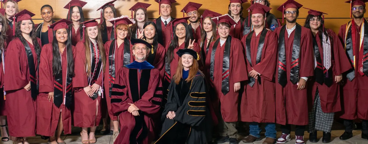 Donaghey Scholars graduates in maroon caps and gowns with program faculty