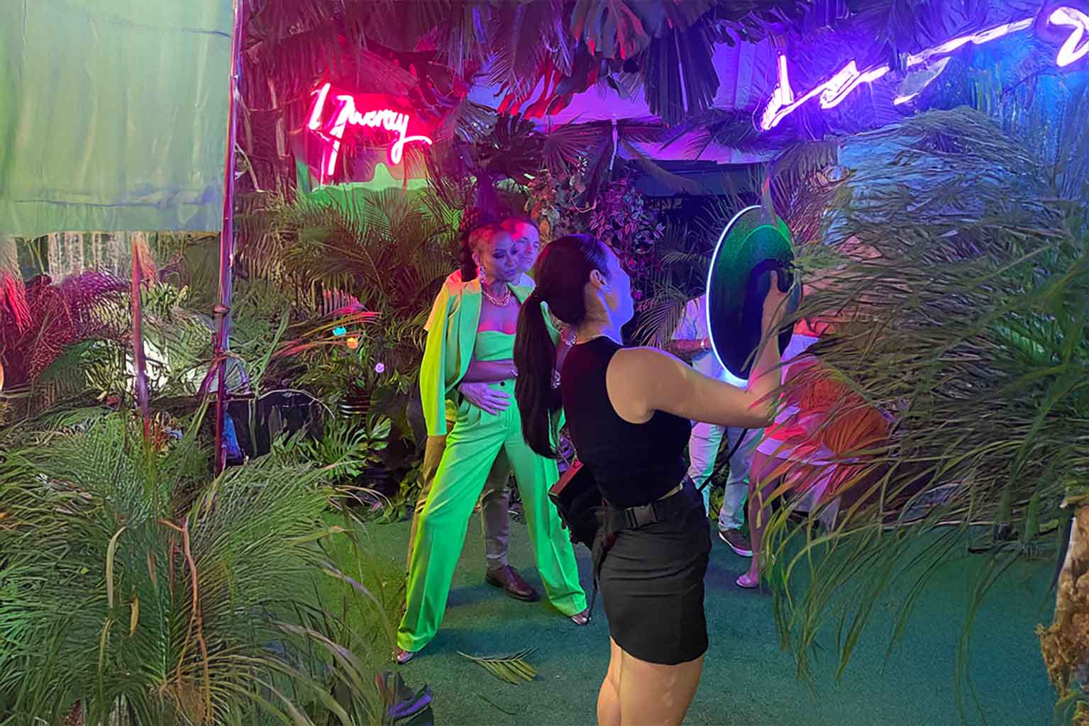 Guests striking poses at a red carpet gala in Miami with the Roaming Photo Booth, surrounded by vibrant lighting and tropical décor for a cinematic experience.