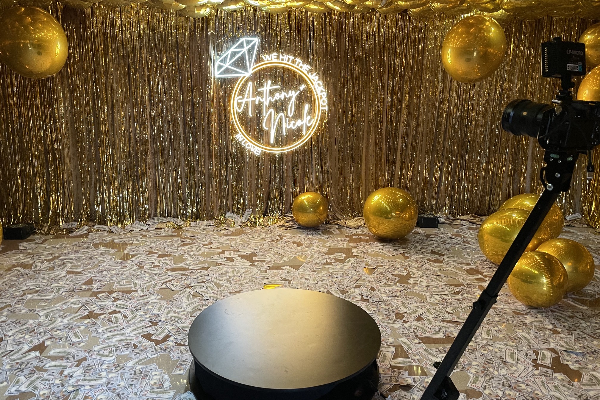 Gold jackpot-themed engagement photo booth setup with rotating platform and camera arm at a Miami luxury event