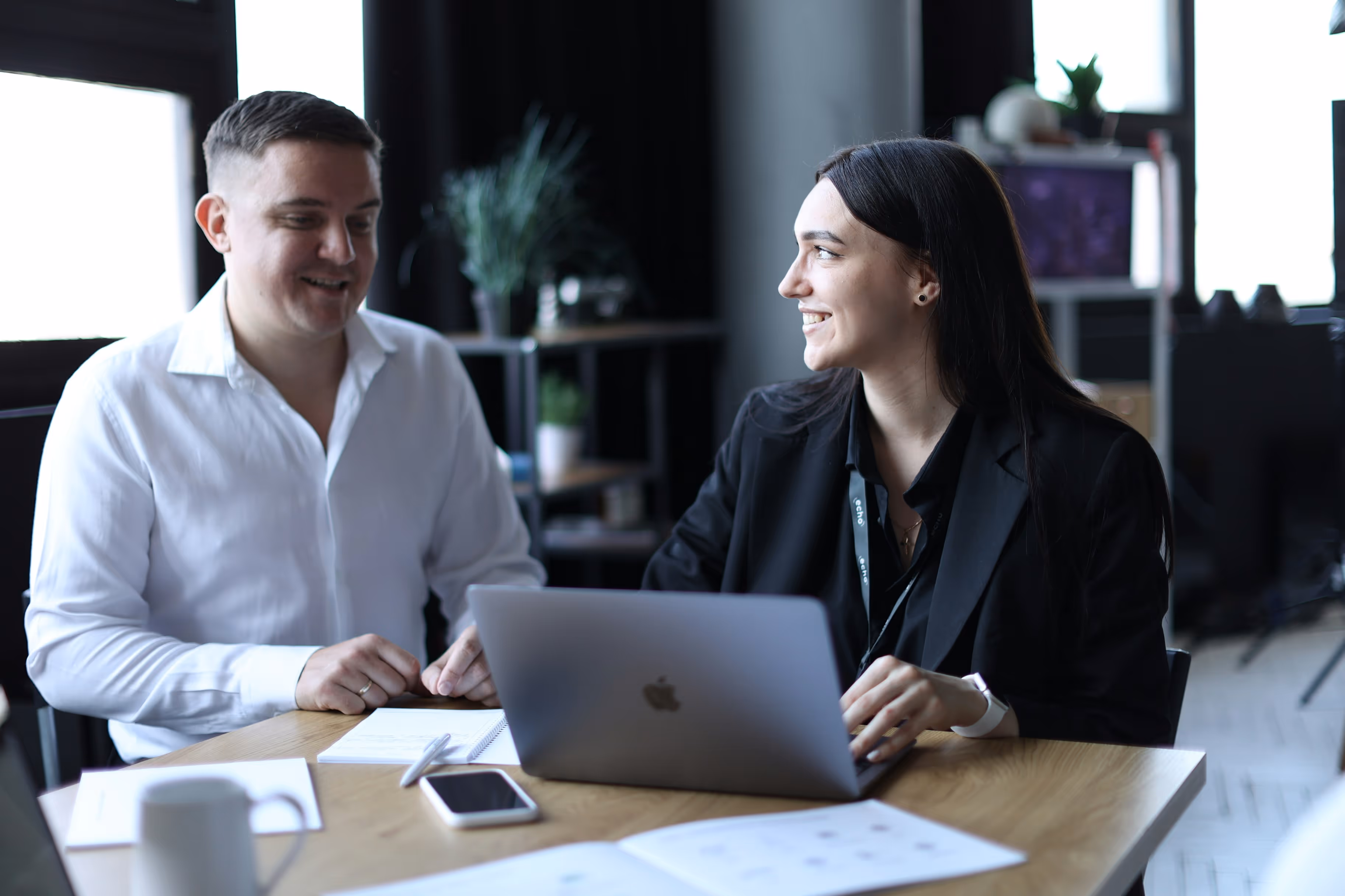 Women sitting at desk with computer and smiling with colleague 
